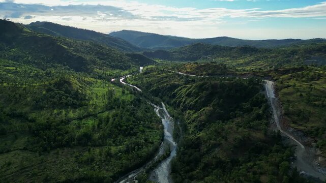 Slowdown Aerial revealing sweeping curves, rolling terrain, and glowing sky above vast countryside at Daang Kalikasan Aguilar Mangatarem Pangasinan Philippines