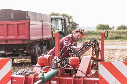 Farmer on field examining farm machine