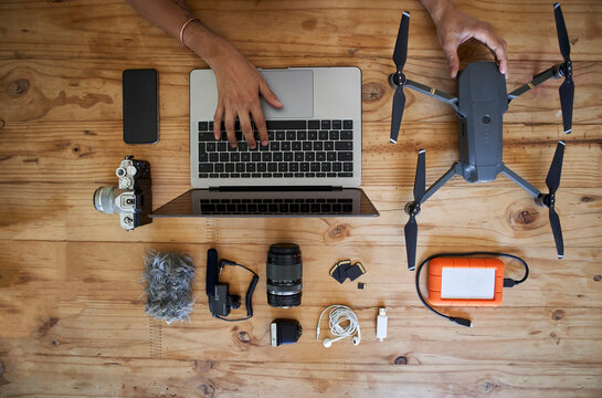 Person sitting at table with photografic equipment, using laptop, overhead view