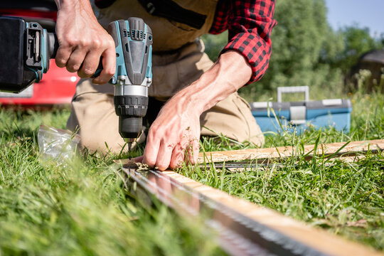 Carpenter holding drill on plank