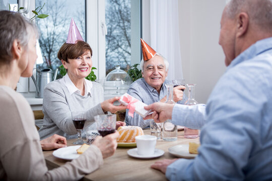 Two senior couples celebrating birthday party, toasting with red wine