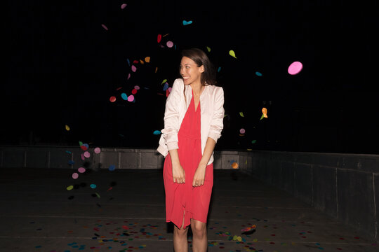 Young woman standing on a rooftop terrace with flying confetti