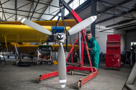 Mechanic in hangar pushing propellor of light aircraft