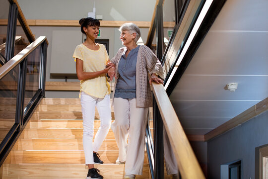 Nurse helping senior woman to walk down the stairs