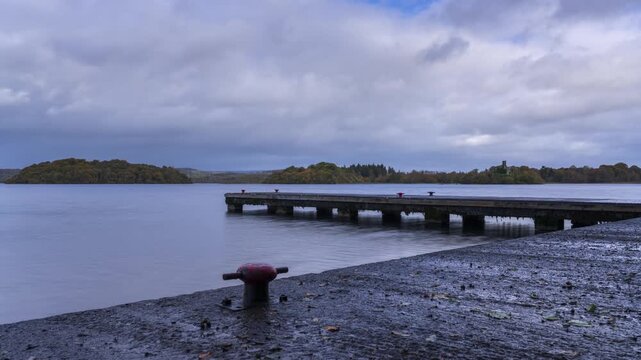 Timelapse of a concrete lake pier area with forest in distance on a mostly cloudy day at Lough Key in county Roscommon in Ireland.