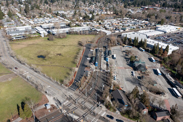 Fototapeta premium Aerial drone view of Beaverton Transit Center in Oregon USA with MAX light rail train and public buses at urban transportation hub. Rail tracks, station buildings commuter infrastructure 