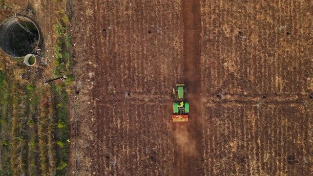 Aerial drone view of Adgaon, Nashik farmland during harvest, golden crops swaying, tractors at work, farmers reaping, sunlight highlighting rural life and agricultural abundance in Maharashtra