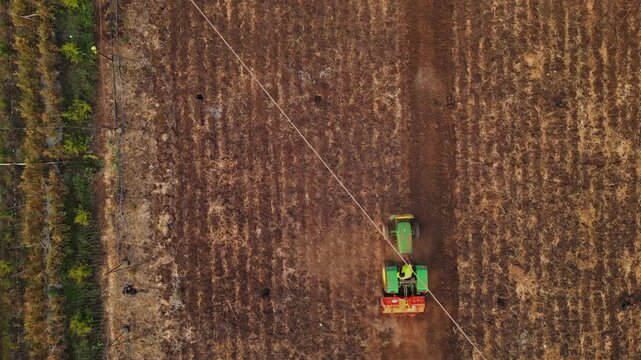 Drone view of lush green and golden fields in Adgaon, Nashik, Maharashtra, with neat crop patterns, a tractor at work, and serene rural beauty under bright sunny skies