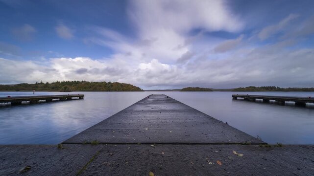 Timelapse of a concrete lake pier area with forest in distance on a mostly cloudy day at Lough Key in county Roscommon in Ireland.