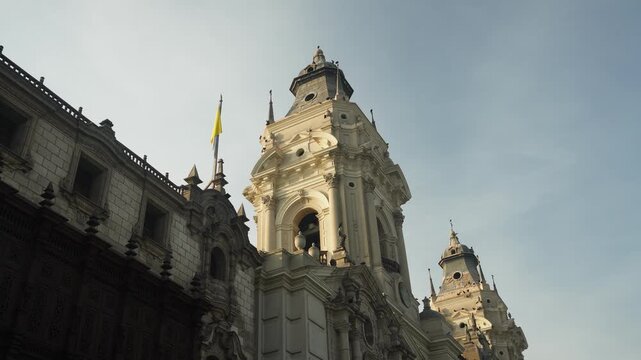 Basilica Cathedral of Lima. Camera points upward at the top portion of the building bathed in morning sunlight while the bottom portion remains in shadows. Located in the city center of Lima, Peru.