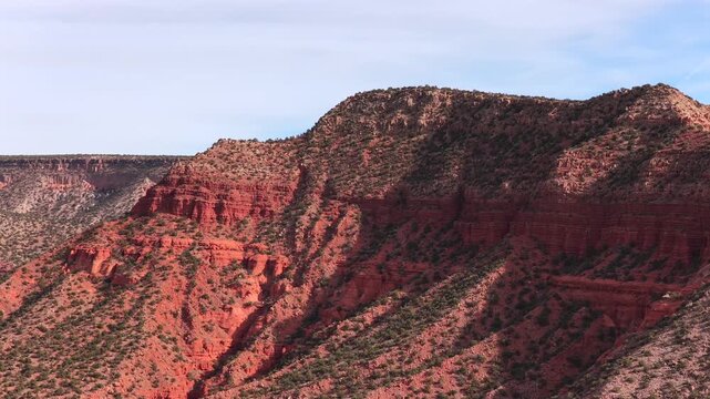 Explore the monumental scale of weathered crimson cliff faces. This 4K drone perspective features the rugged verticality and natural textures of a remote New Mexico canyon system.