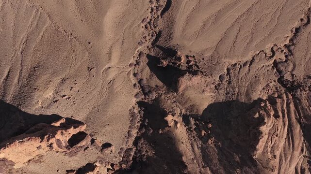 An overhead drone perspective reveals the complex, organic erosion of a desolate basin. These sharp shadows and primeval soil patterns create a perfect alien world background.