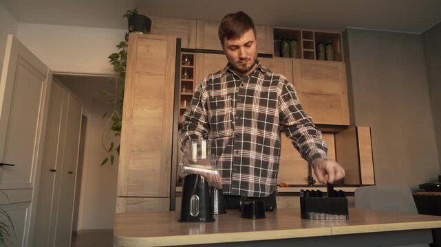 A male householder in the kitchen is assembling a manual vegetable slicer.