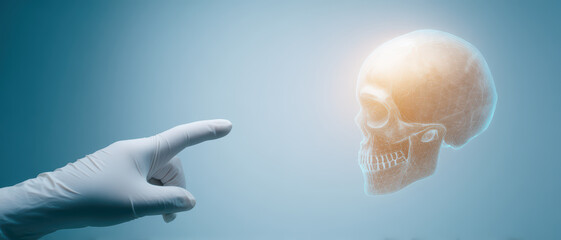 Obraz premium Close up of hand wearing medical glove pointing at glowing human skull x ray on blue background, symbolizing medical or dental examination and care