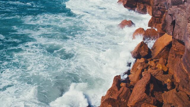  Crashing waves creating huge splashes.  Ocean Waves at high tide roll in and crash against the coastal cliffs, huge rocks. Top view of the coastal cliffs with large waves crashing against the rocks