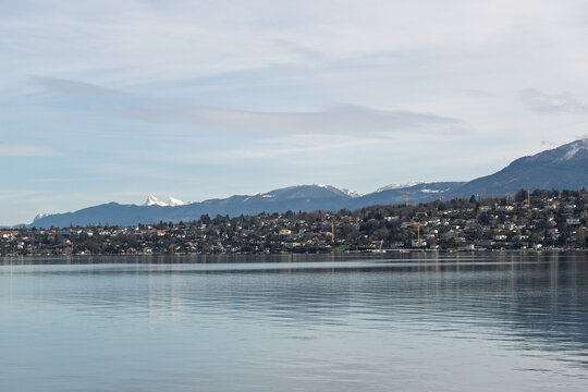 Panorama hivernal du lac L&eacute;man &agrave; Gen&egrave;ve avec montagnes enneig&eacute;es et communes riveraines