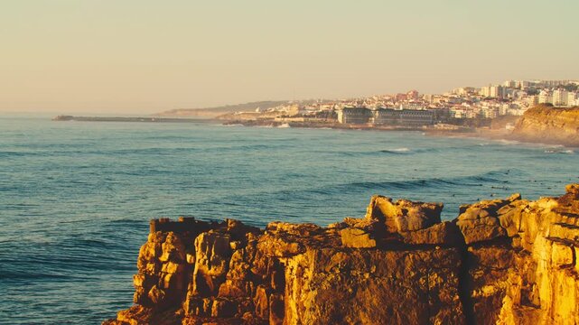 Beautiful view of the rocky coastal European city in the sunny evening sunset. Beautiful evening sunset on the background of the endless ocean. The concept of tourism and recreation.