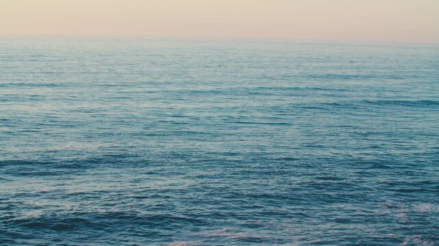 The endless ocean.  The blue water surface of the endless ocean on a sunny day.  Top view of the calm ocean in the afternoon. A soothing seascape with a clear and cloudless sky on the horizon