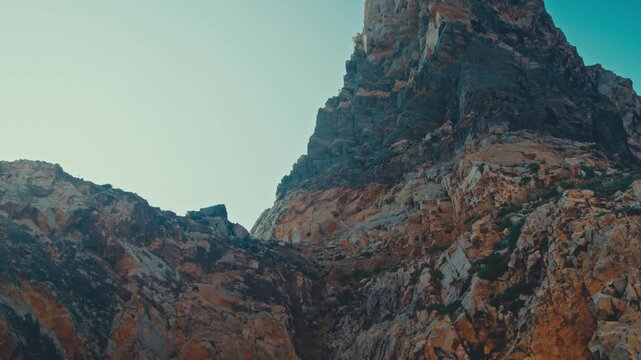Beautiful jagged rock against the blue sky on a sunny summer day. The camera moves from top to bottom from the top of the cliff to its base. Beautiful natural landscape.