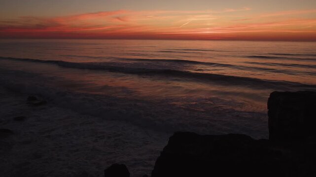 A magnificent colorful sunset colors the evening ocean calm waves. The water surface mirrors the picturesque vibrant scene of the ocean sunset. Beautiful seascape during sunset.