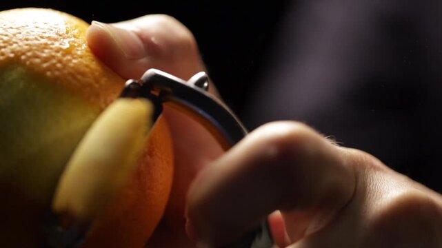 Bartender peeling an orange for zest the cocktail. Old fashioned drink.