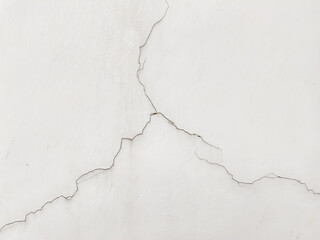 Obraz premium Close-up of a cracked white wall texture with deep fracture lines. This minimalist background features aged plaster and weathered cement details, ideal for architectural and urban decay themes.