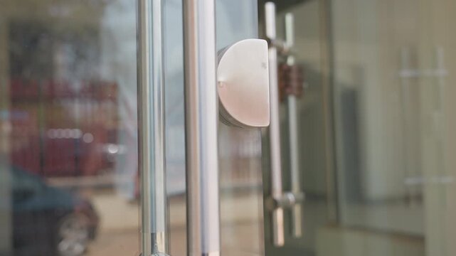 Black man opening glass house door at morning, homeowner arrival captured through reflective stainless handle and clear panes, casual shirt and jeans, street reflection visible, warm sunlight and calm
