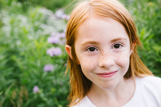 Young girl with freckles and red hair close up of face with flowers