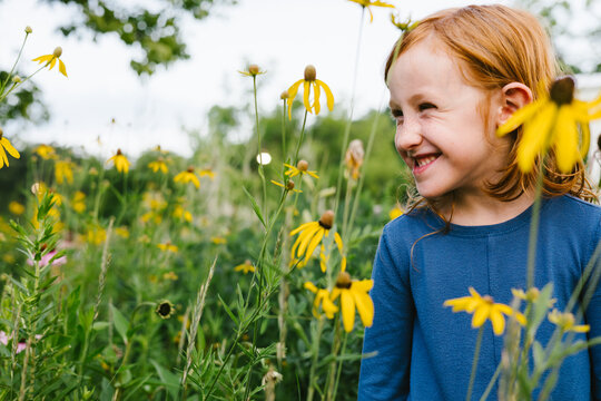 Smiling young red hair girl in field of wildflowers