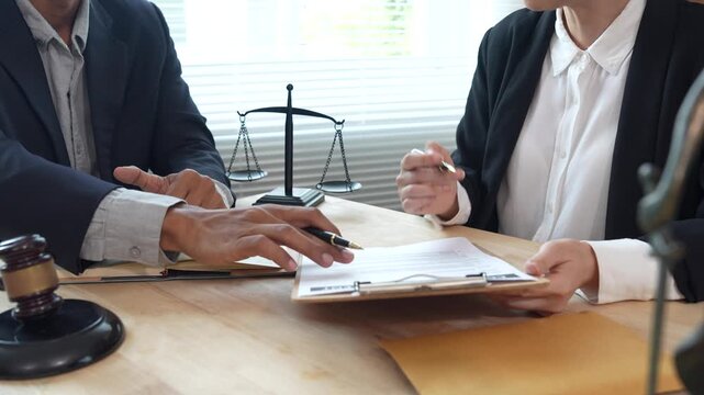 Lawyers reviewing and signing a legal contract at a desk with a gavel and scales of justice, representing legal consultation, agreement process, and professional law services.