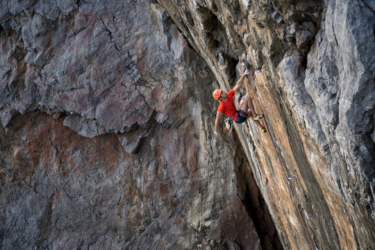 Climber scaling steep sea cliff at Bosherston Head Pembrokeshire UK