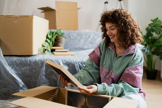Smiling woman unpacking memories in new home living room