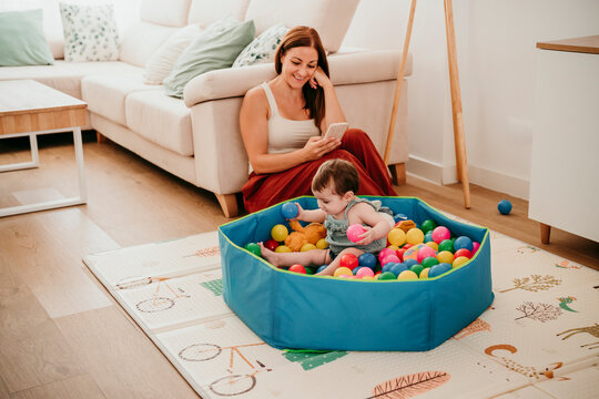 Mother and baby playing with colorful pool balls at home living room