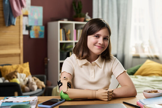 Portrait of smiling amputee kid with prosthesis studying at home