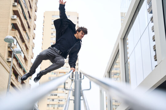 Parkour athlete jumping over rail in urban cityscape outdoors