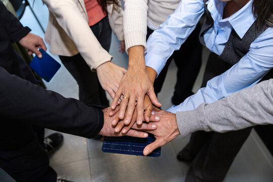 Colleagues stacking hands in office showing teamwork and unity