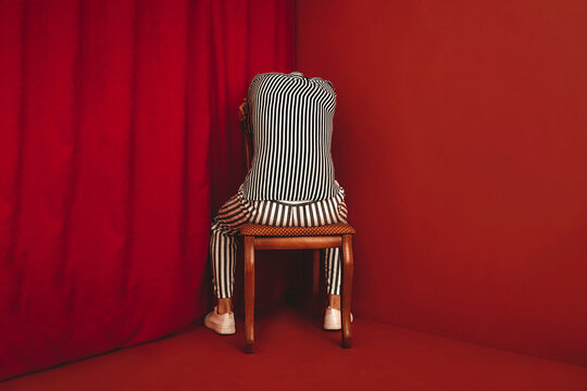 Person in striped clothing sitting in corner depicting depression and burnout