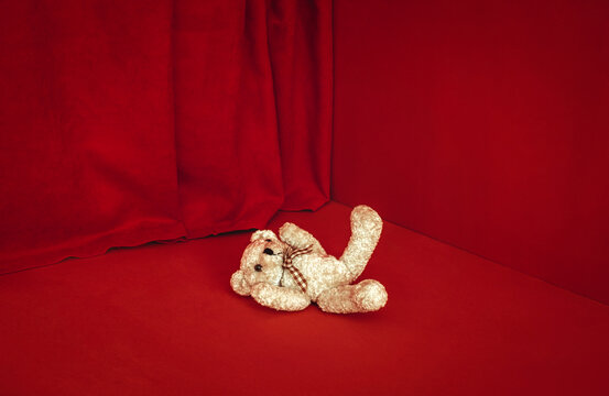 Teddy bear on red background symbolizing childhood anxiety and innocence