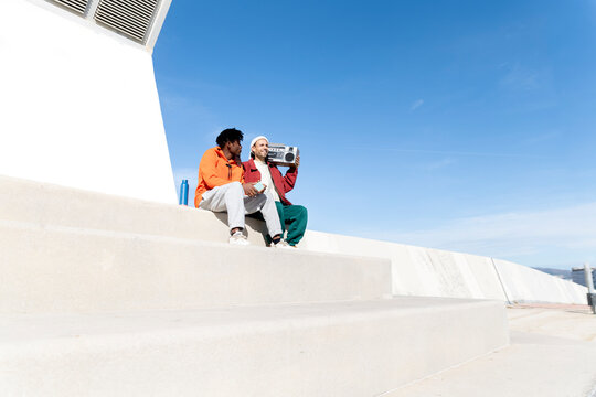 Friends sitting on outdoor stairs in Barcelona with vintage boombox