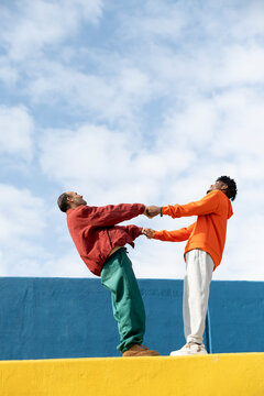 Friends balancing and holding hands outdoors in Barcelona