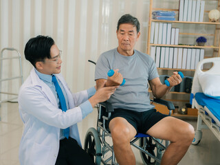 Obraz premium An Asian male doctor recommended dumbbell rehabilitation exercises to an elderly man in a wheelchair at a senior care facility for therapy and strength training.