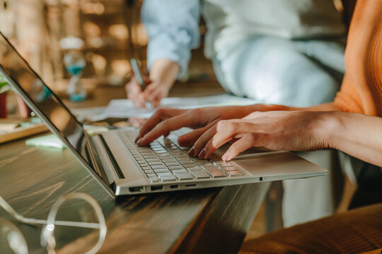 Colleagues collaborating with laptop and notes at modern office desk