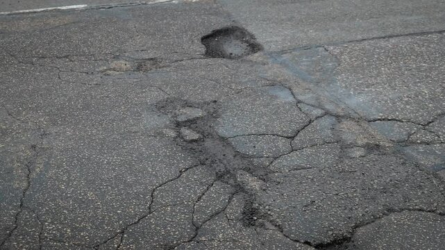 Asphalt Potholes Formed After Winter Freeze Thaw Cycle Showing Road Damage