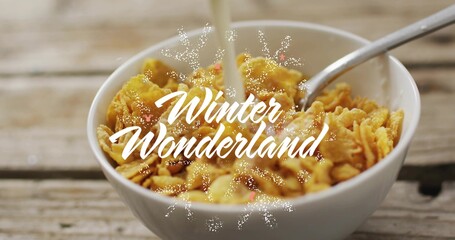 Pouring milk splashing cornflakes in bowl on wooden table, with spoon, Winter Wonderland overlay © vectorfusionart