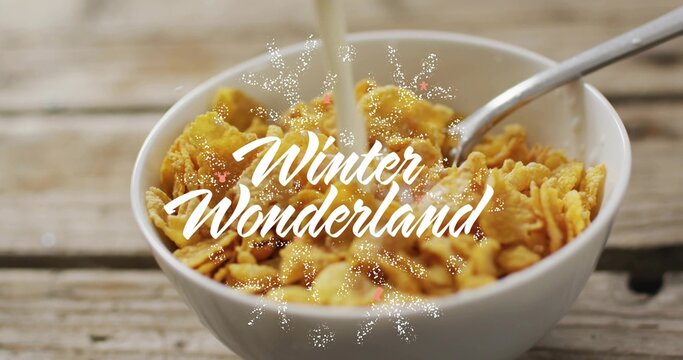 Pouring milk splashing cornflakes in bowl on wooden table, with spoon, Winter Wonderland overlay