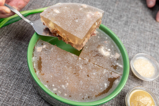 Closeup of traditional Russian holodets (aspic jelly meat) served with mustard and green onion.