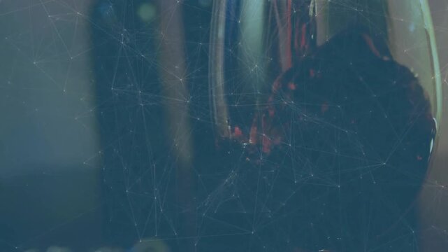 Red wine pouring into stemmed glass from left, liquid swirling, droplets clinging to fill glass