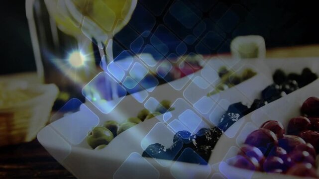 Camera shifting up, tiles drifting right, dish holding olives, wine glass filling, revealing bottle