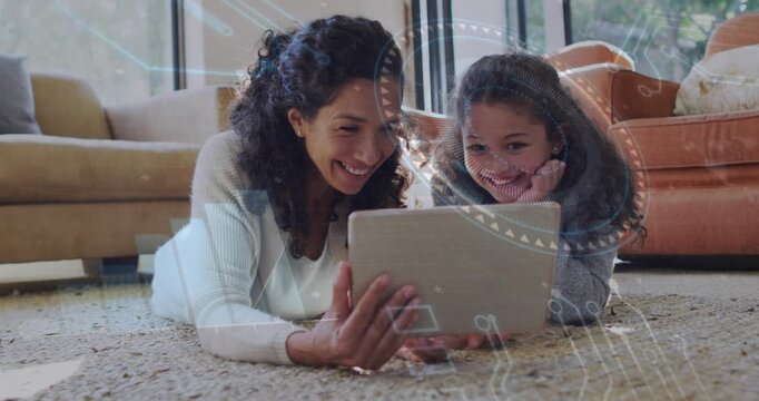 Mother tilting tablet and sharing learning app with daughter on rug while animated HUD appearing