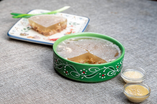 Closeup of authentic traditional Russian holodets (aspic jelly meat) served with mustard and fresh green onion, homemade food.